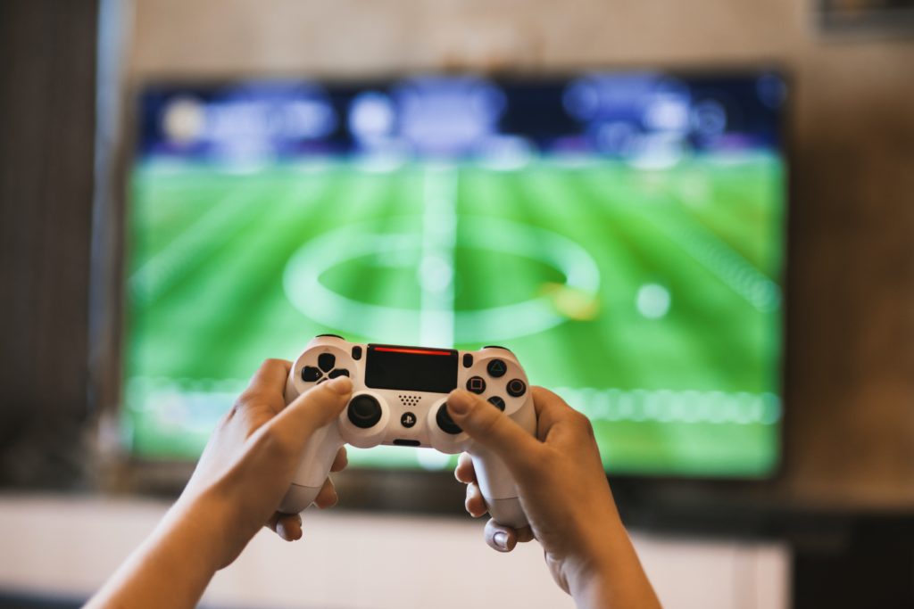 Playing a football simulation video game with a PlayStation controller. (Image: Pexels /  EVG Kowalievska)